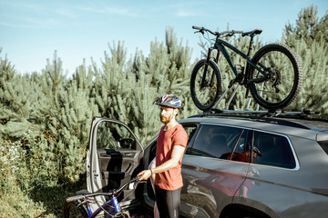 Man preparing for the bicycle riding, picking up mountain bicycle from the car trunk during the summer in the forest © rh2010
