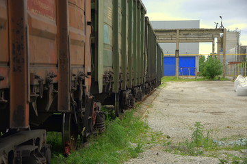Railroad cars in a dead end at an old abandoned factory at the blue gate of the warehouse. Summer.