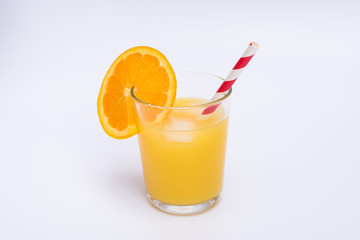 Orange juice in a glass with ice and paper straw on white background