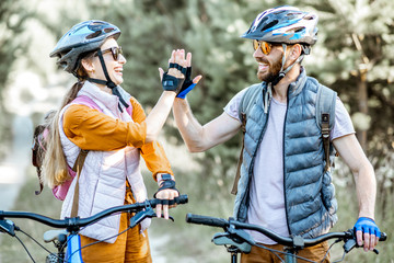 Young and active couple giving a five each other, having fun while traveling with bicycles on the...