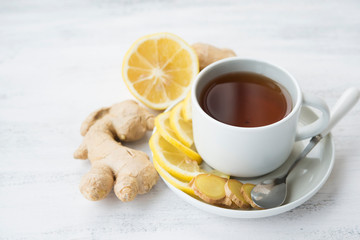 Cup of black tea with ginger and lemon on a light background. 