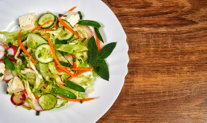 Summer salad of vegetables and cheese in a plate. There is room for text