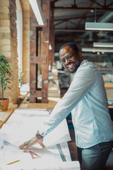 Dark-skinned interior designer smiling while working hard
