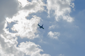Fototapeta na wymiar flying airplane in the blue sky with clouds