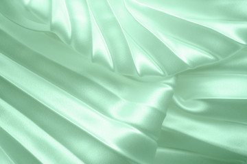 Neo mint color soft satin folded fabric background texture. Close up of ripples on silk fabric. Neo...