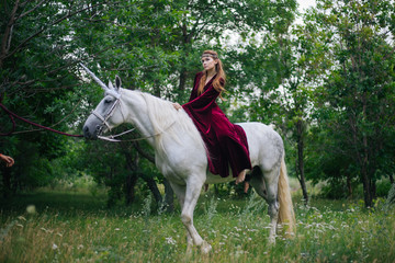 Beautiful girl in red medieval dress with unicorn. Fantasy. Woman Elf