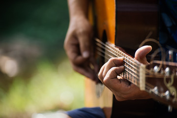 travel, tourism, hike, leisure concept -  Hipster guy classic guitar practice by hand, Happy man playing aoustic guitar at camping,close up,copy space for text.