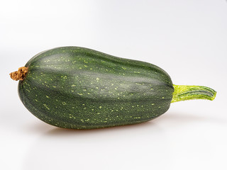 Large ripe green zucchini on a white background, close-up. Still life.