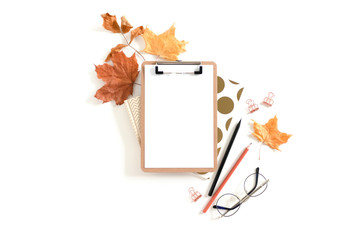 Clipboard mockup with frame made from dry maple leaves, glasses and stationery on white background