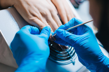 Manicurist. A girl with blue gloves makes a manicure. The process of manicure.