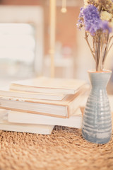 Fototapeta na wymiar close up books stacking and vase dry purple flower on table in room and warm light
