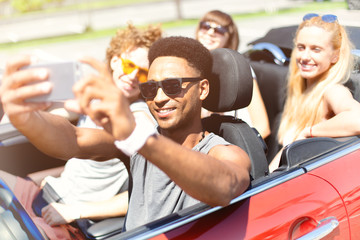 Young friends take a selfie in a cabriolet car