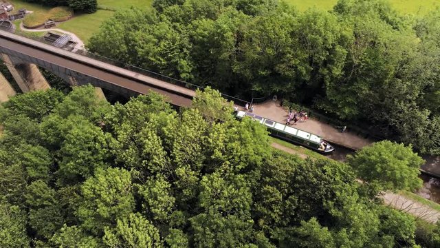 Pontcysyllte Aqueduct arch bridge canal waterway crossing. Aerial tracking boat travelling down canal.