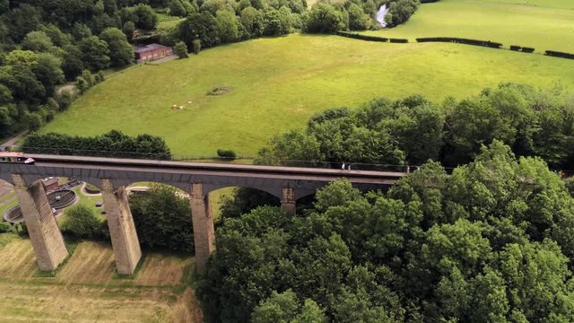Pontcysyllte Aqueduct arch bridge canal waterway crossing. Aerial pull back reveal of boat crossing structure.