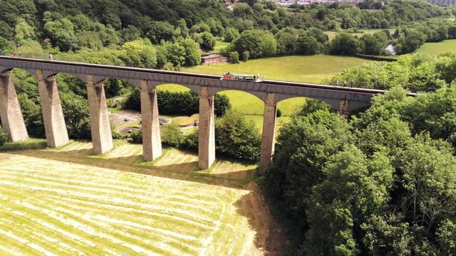 Pontcysyllte Aqueduct arch bridge canal waterway crossing. Descending aerial as boat crosses structure.
