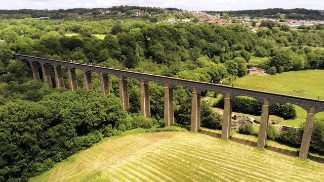 Pontcysyllte Aqueduct arch bridge canal waterway crossing. Descending aerial view of people walking across structure.