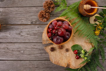 Harvest ripe fruit. Background with fern leaves, red plums and grapes. Vintage on aged wood with copy space. Layout for seasonal offers, top view.