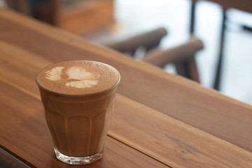 Piccolo Latte art in small glass on wooden desk