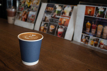Piccolo Latte art in paper cup on wooden desk