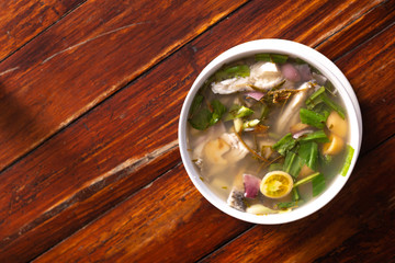 Spicy fish soup flavored with lemongrass and lime served on wooden table