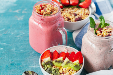 Bowl of homemade granola with yogurt and fresh berries on wooden background