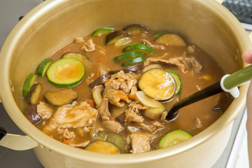 キッチンのコンロで大きい鍋で夏野菜でカレーを作っている