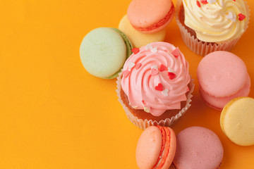 Delicious cupcakes with icing on a yellow background