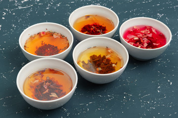 Tea concept. Different kinds of dry tea in ceramic bowls and cups of aromatic tea