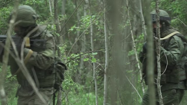 Patrol soldiers in camouflage with assault rifle walking through the forest, military action in the woods, special forces group.