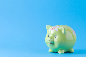 Green pig money box on a bright blue background. Finance, savings, money. space for text