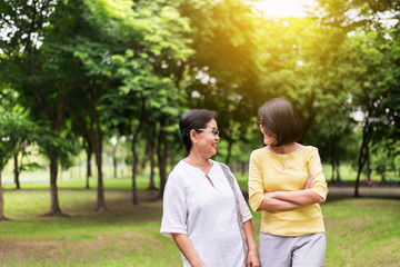 Fototapeta premium Take care and support concept,Portrait of middle aged asian woman with daughter standing and hugging together outdoor,Happy and smiling,Positive thinking