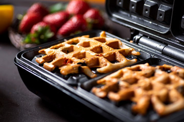 Waffle pastry baking on a waffle maker close up