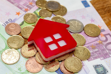Red home house on the banknotes background euro dollar pile pack real estate concept expenses property buying mockup copy space close up background selective focus