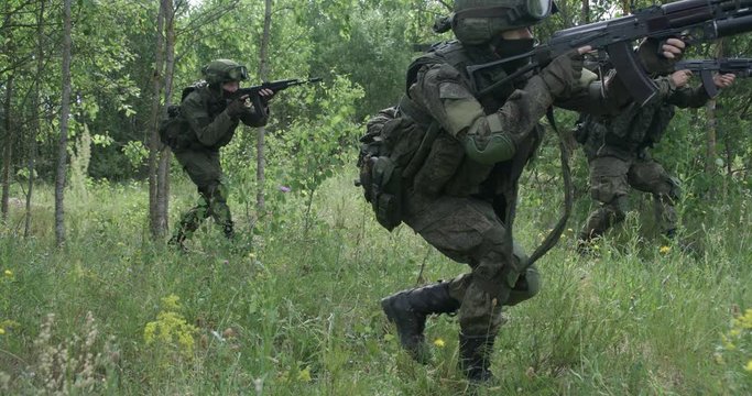 Special forces group in camouflage with assault rifle, military action in forest, patrol, soldiers go on the attack.