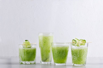 Set of glasses of cucumber smoothie on the white table against white wall.Empty space for text