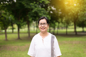 Portrait of senior asian woman wearing glasses showing thumb up at public park,Happy and smiling,Positive attitude thinking.