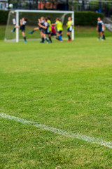 White outline for a football field for a Girl's Under 15 years school soccer tournament. Focusing on the football field with blurry football players in action as a background.