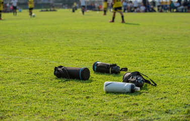 Sport plastic bottles of fresh water left on a football field while players having a match on a pitch as seen in a background.