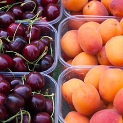 Barquettes de cerises et d'abricots sur l'étalage d'un marché aux fruits