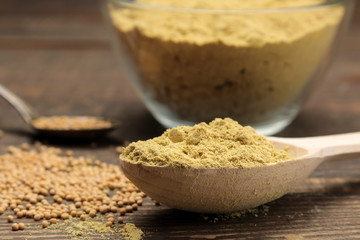 Mustard Mustard powder in a wooden spoon on a brown wooden table. close-up.