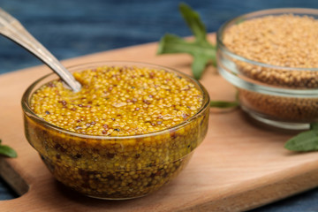 french mustard in a bowl and dry mustard seeds on a blue wooden table. close-up.