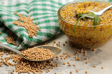 Mustard sauce, French Mustard in a bowl and dry grains on a light concrete table. close-up.
