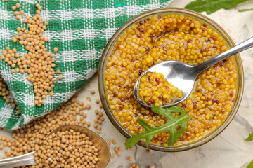 Mustard sauce, French Mustard in a bowl and dry grains on a light concrete table. close-up. top view