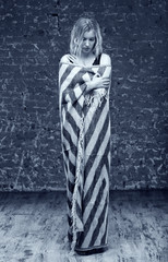 Obraz premium Female fashion model in wool blanket on brick wall background. Woman photo tinted in blue color.