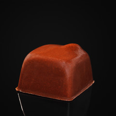 Candies made of milk chocolate in the shape of a square on a black background.