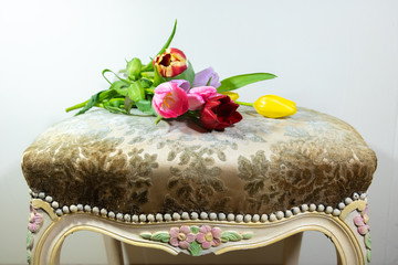 Bouquet de tulipes multicolores posé sur un siège vintage très féminin recouvert de tissu.