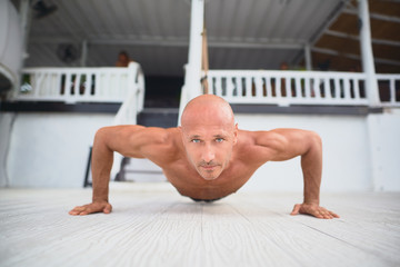 Obraz premium Young and handsome man is doing some push-ups. He is using loops for that 