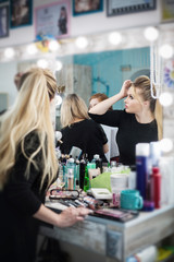 Woman in a beauty salon looks at her reflection in the mirror on her makeup and hairstyle.