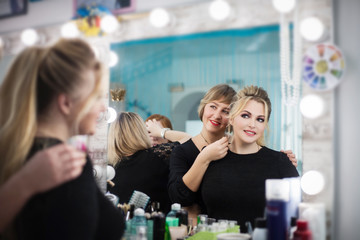 Two beautiful young women look in the mirror in the beauty salon. Hair and makeup.