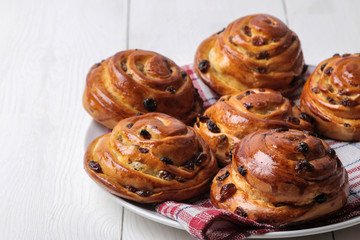 Delicious buns with raisins on a plate on a white wooden table. fresh bakery. breakfast. bread.